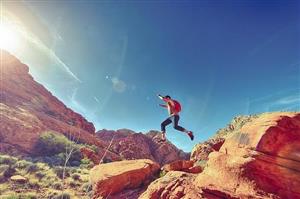 man jumping off red rocks